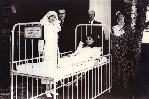 People standing beside a hospital bed.